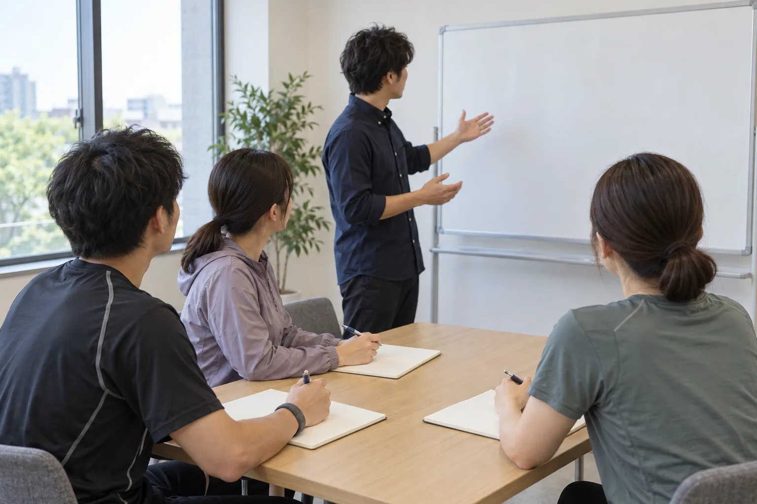 会議室で、講師の説明を聞きながらノートを取るトレーナーたち。